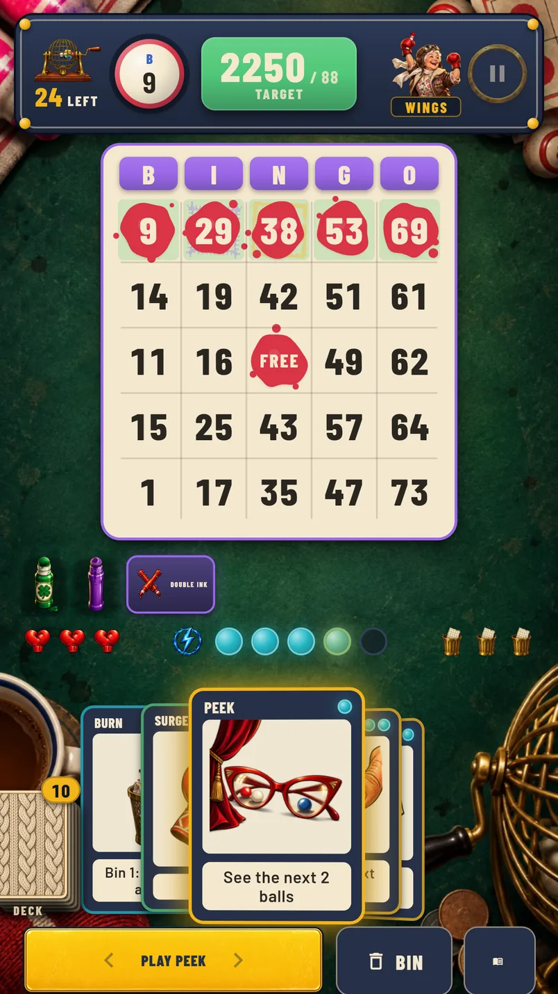 A bout in progress: the bingo ticket on the green baize, the called ball, the target score, and a hand of dabber cards along the bottom.